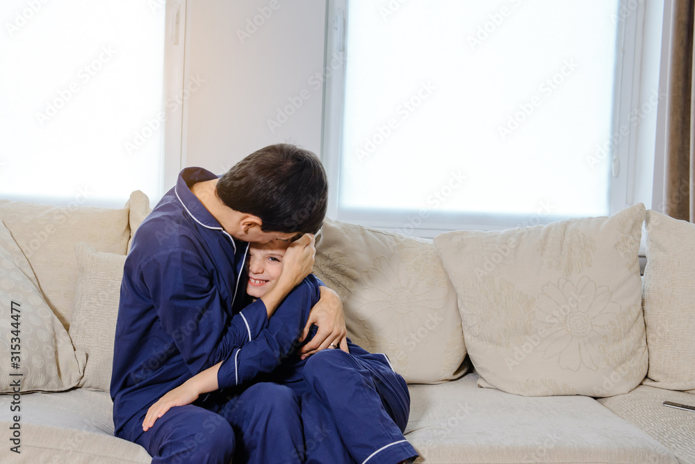 Happy young father lying on bed and playing with his son