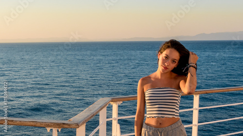 Fotografia Teen girl in shorts on deck of ferry boat holding hair
