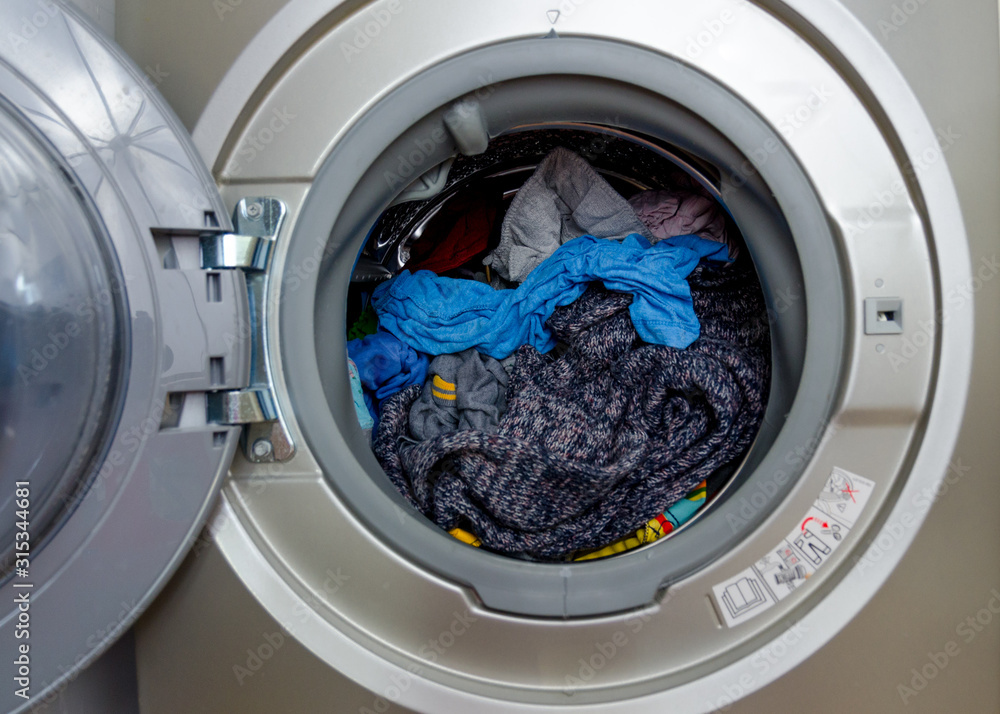 Washing machine with dryer, freshly washed clothes and dried in combined washing machine. Colored clothes, open doors, rubber seal, stainless drum, clean clothes Washing machine with dryer, freshly washed clothes and dried in combined washing machine. Colored clothes, open doors, rubber seal, stainless drum, clean clothes