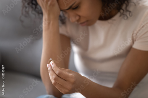 Close up view unhappy african woman holding wedding ring