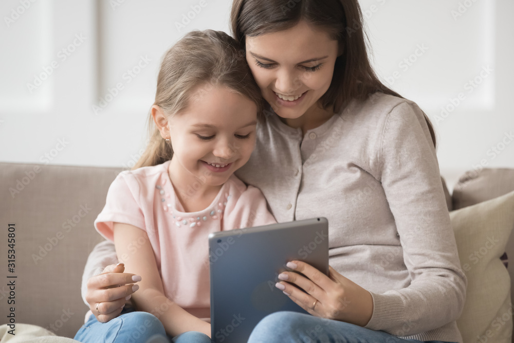 Smiling mother and little daughter using tablet computer together Smiling mother and little daughter using tablet computer together