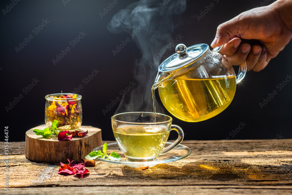 Hot tea in glass teapot and cup with steam on wood table Hot tea in glass teapot and cup with steam on wood table