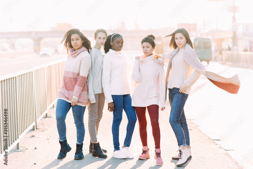 Multiracial group of friends from five young women walks on city street. Multiracial group of friends from five young women walks on city street.