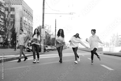 Multiracial group of friends runs and has a fun on city street. © Stanislav