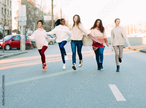 Multiracial group of friends runs and has a fun on city street.