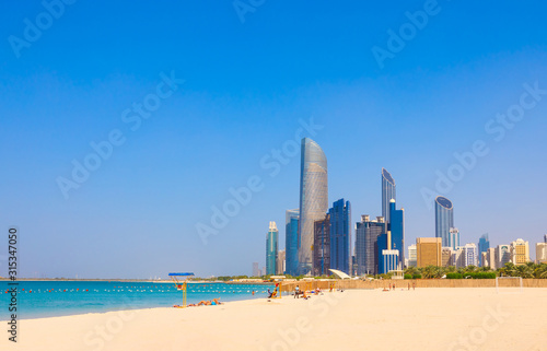 Skyline view of Abu Dhabi panorama with sea, beach and skyscrapers. Sunny summer day in Abu Dhabi - famous tourist destination in UAE. Ideal place for luxury travel and rest