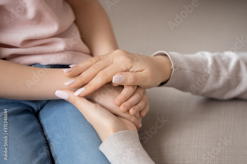 Close up loving mother holding child hands, showing love and support