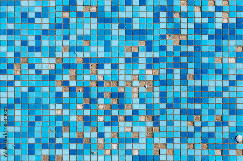 Damaged surface with blue square tile mosaic. Broken surface with missing pieces of tiles.