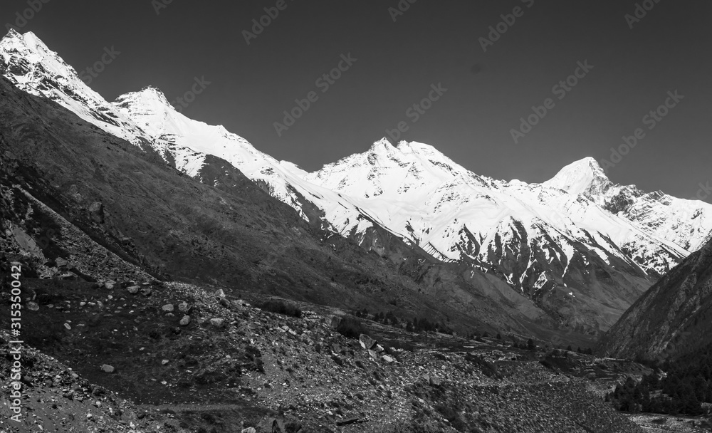 Black and white shot of the Himalayan mountains towering over the fields in the village of Chitkul in Kinnaur, India.