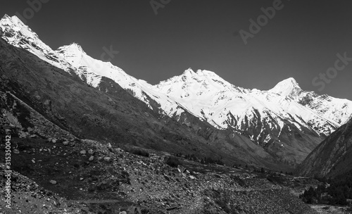 Black and white shot of the Himalayan mountains towering over the fields in the village of Chitkul in Kinnaur, India.
