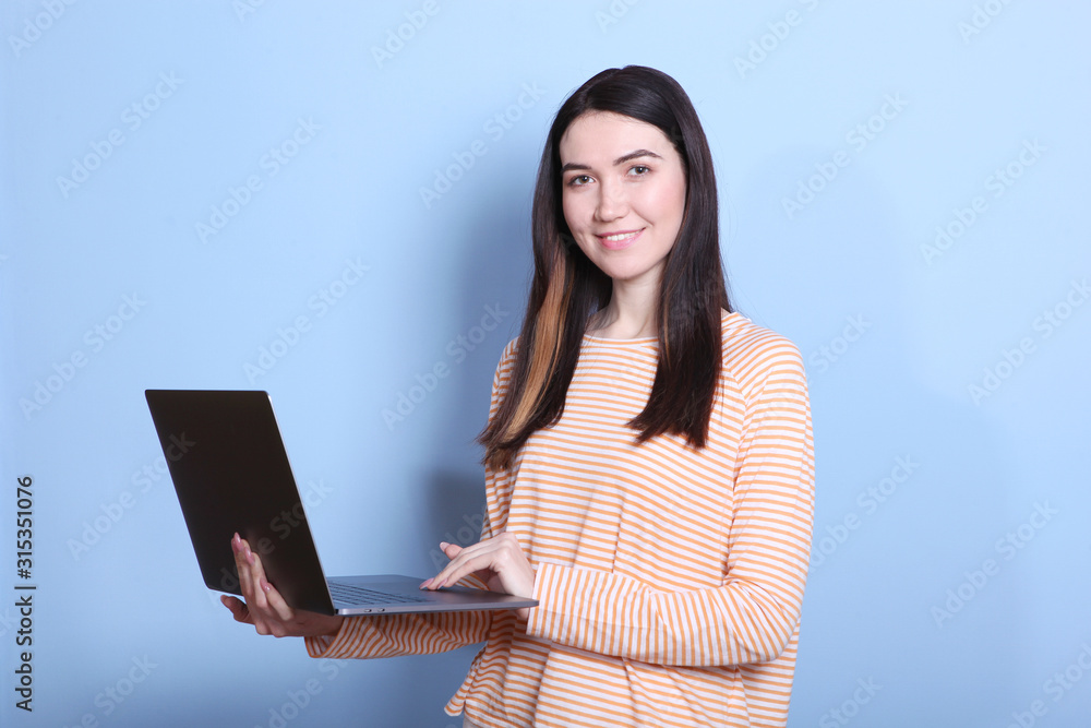 Naklejka premium girl holds a modern laptop on a colored background.
