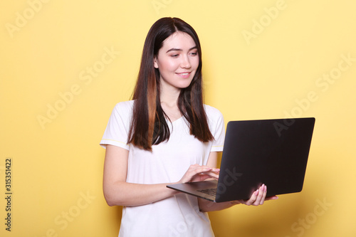 girl holds a modern laptop on a colored background.