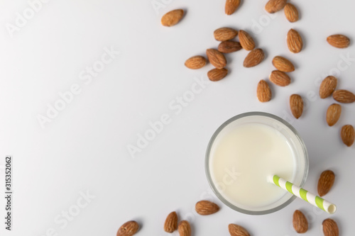 Glasses with almond milk and nuts around it on white background, copy space