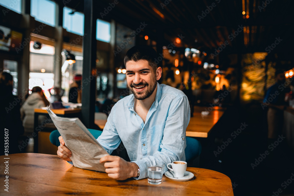 man reading newspapers and drinking coffee in cafeteria man reading newspapers and drinking coffee in cafeteria