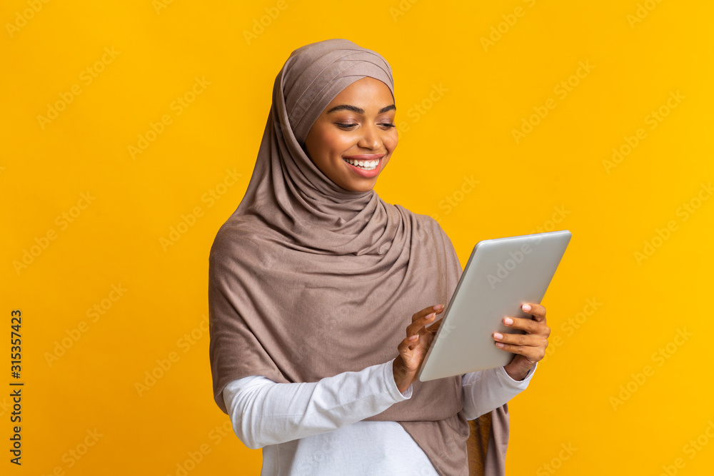 Portrait of smiling afro muslim girl in hijab using digital tablet Portrait of smiling afro muslim girl in hijab using digital tablet