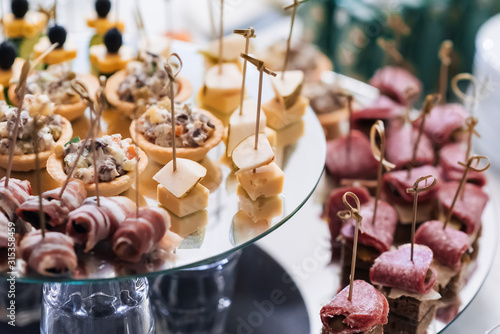 canapes with bacon, cheese, sausage, pears and other snacks on the festive table