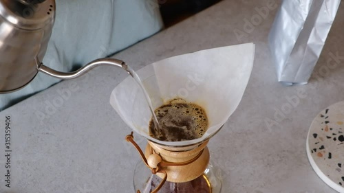 Video of female barista preparing chemex brew coffee. Pouring water with pour over steel kettle. Female barista at work. photo