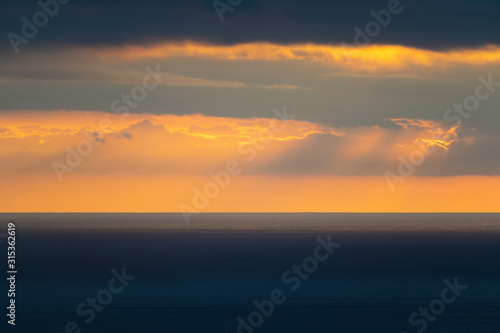 Long aerial view of low clouds over Tasman sea at Piha in sunset light