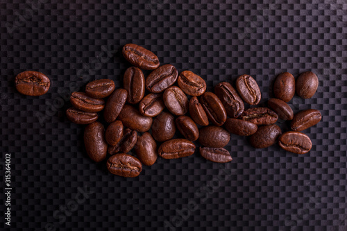 Roasted brown coffee beans on black carbon table or dark background.