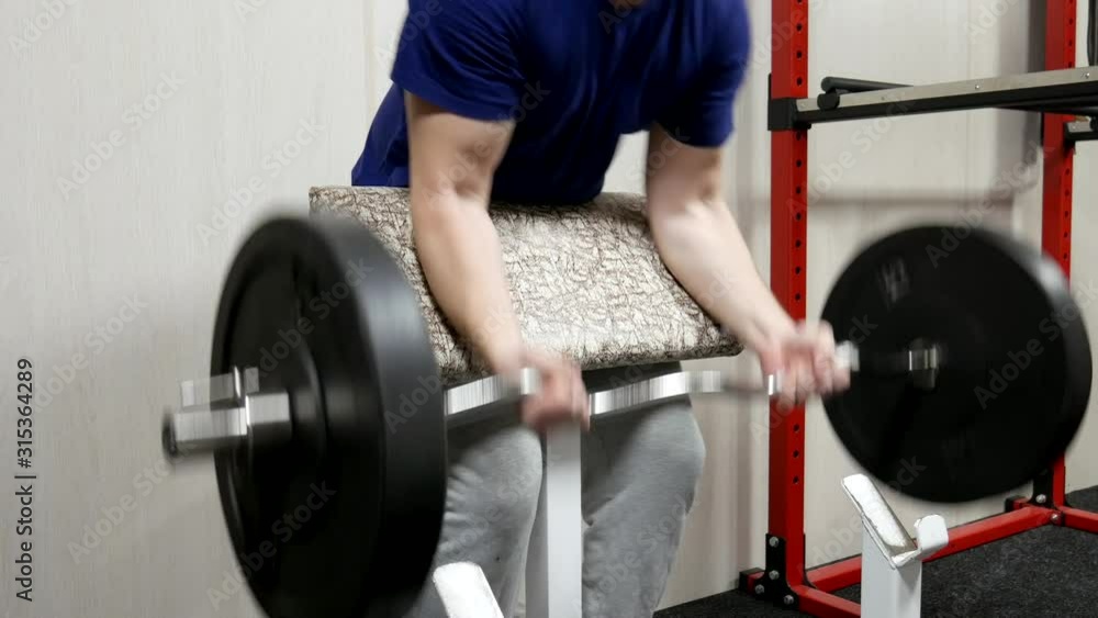 Strength training arm biceps with barbell. Strong man lifts a barbell Strength training arm biceps with barbell. Strong man lifts a barbell