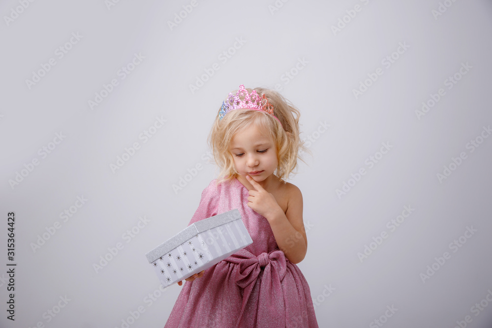cute little girl in a princess dress with a crown holding a gift on a white background cute little girl in a princess dress with a crown holding a gift on a white background