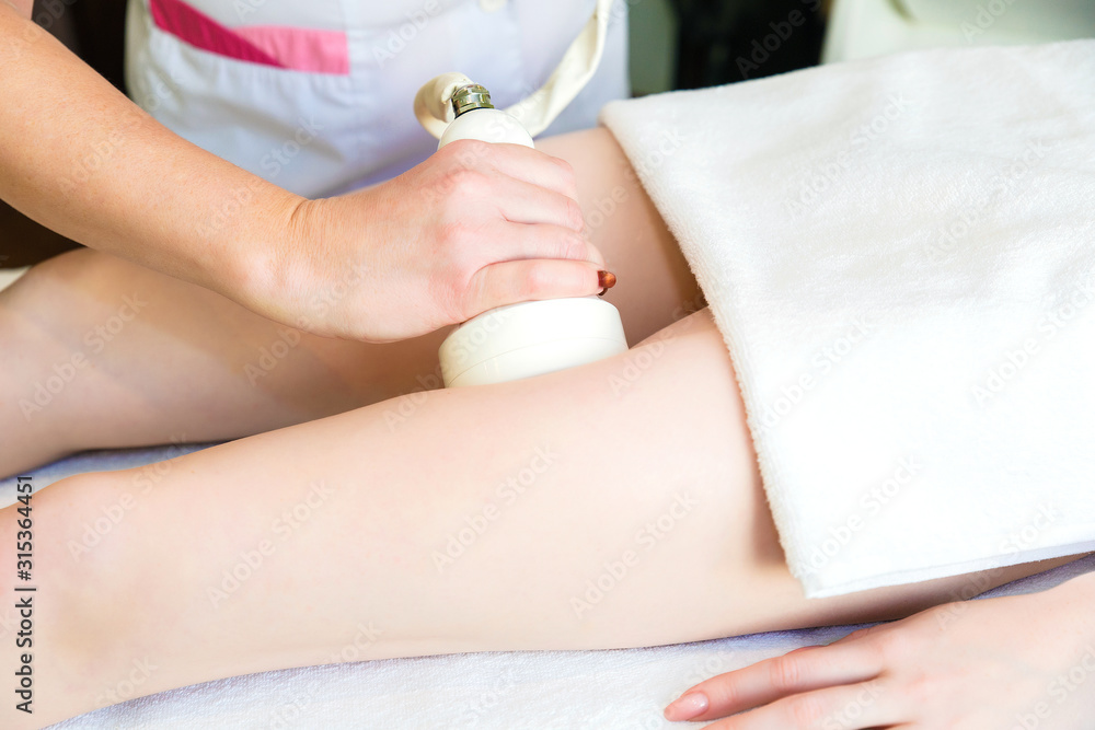 Body massage by cavitation. A young girl on a massage table anti-cellulite massage of thighs. Body massage by cavitation. A young girl on a massage table anti-cellulite massage of thighs.