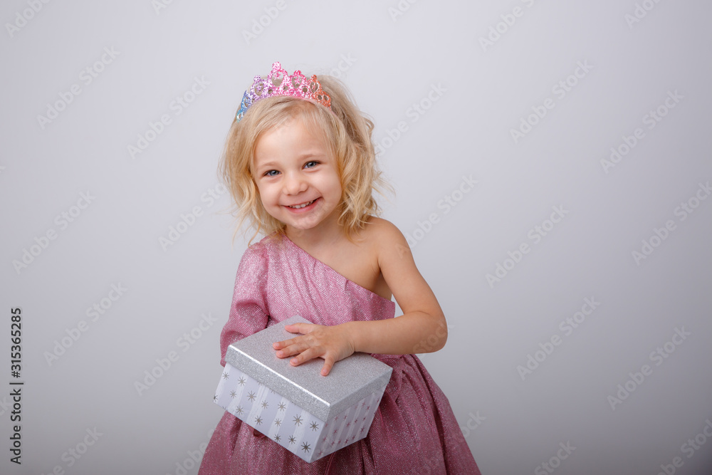 cute little girl in a princess dress with a crown holding a gift on a white background cute little girl in a princess dress with a crown holding a gift on a white background