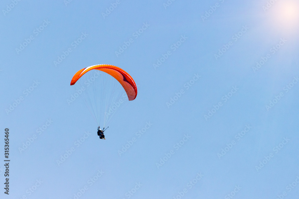 A sportsman flies in the sky in a good suit on a paraglider. Paragliding Sport Concept A sportsman flies in the sky in a good suit on a paraglider. Paragliding Sport Concept
