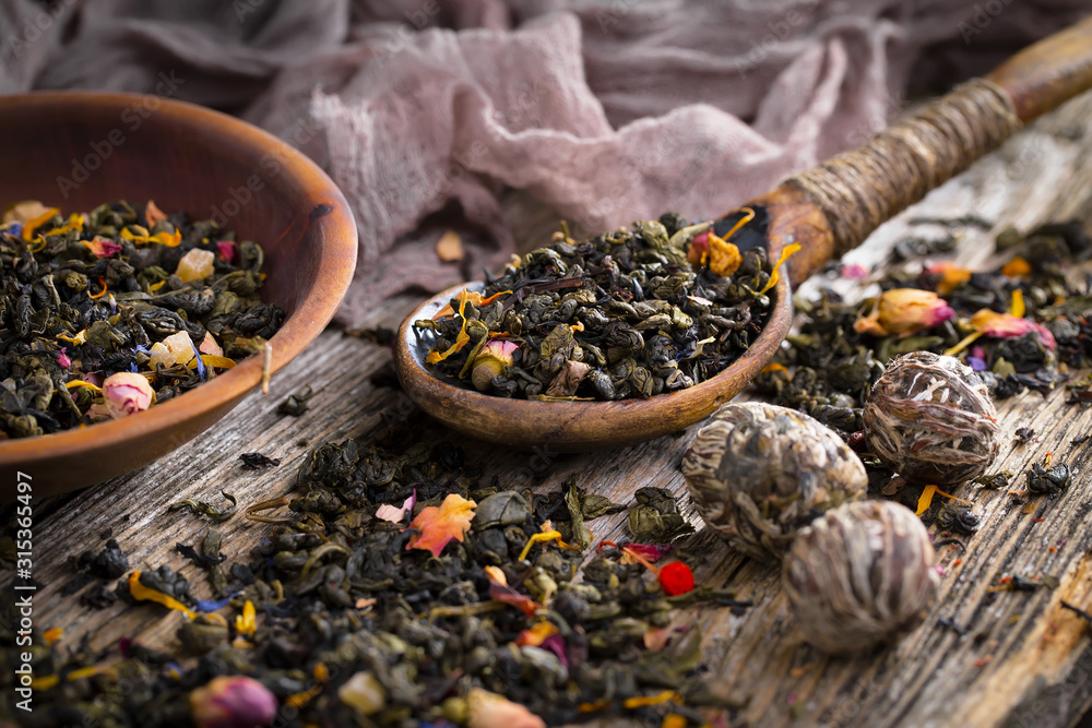 Dry tea leaves on a table in a composition with accessories for tea drinking