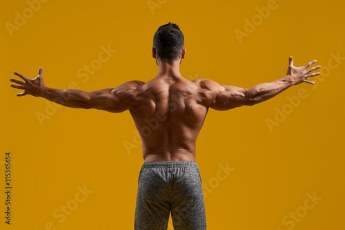 Fototapeta Athletic gentleman posing on yellow background
