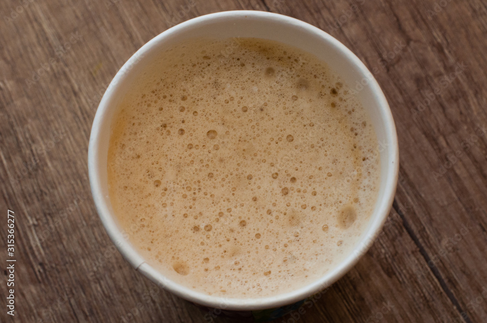 Cappuccino with a delicious foam in a paper cup, top view, coffee to go Cappuccino with a delicious foam in a paper cup, top view, coffee to go