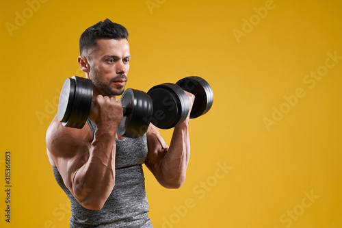 Muscular bodybuilder doing exercise with dumbbells