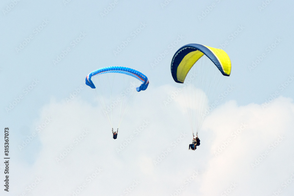 A group of sportsmen flies in the sky in a professional suit on a paraglider. Paragliding Sport Concept for advertising A group of sportsmen flies in the sky in a professional suit on a paraglider. Paragliding Sport Concept for advertising