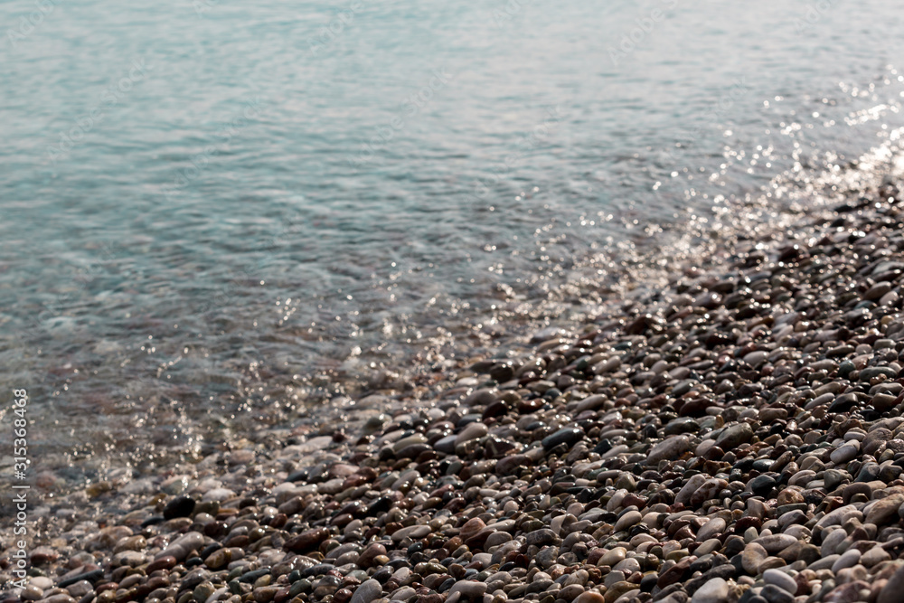 Pebble beach in the sunlight on the famous turkish Konyaalti Beach, Antalya, Turkey