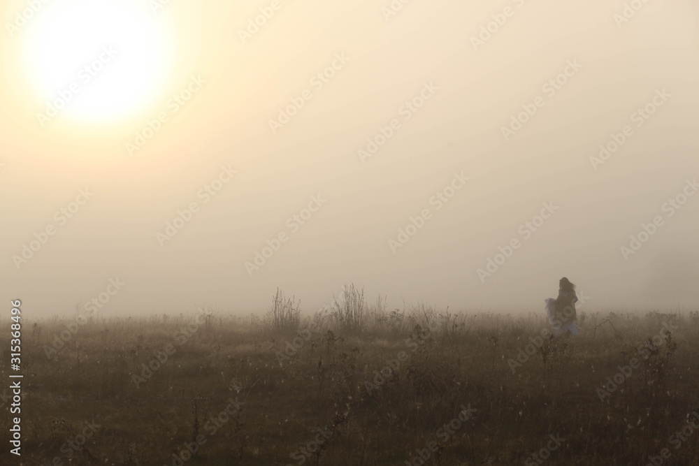 girl in a white dress on a mist field with oaks