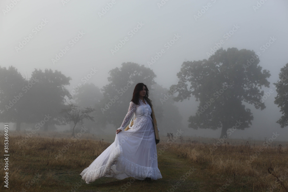 girl in a white dress on a mist field with oaks girl in a white dress on a mist field with oaks