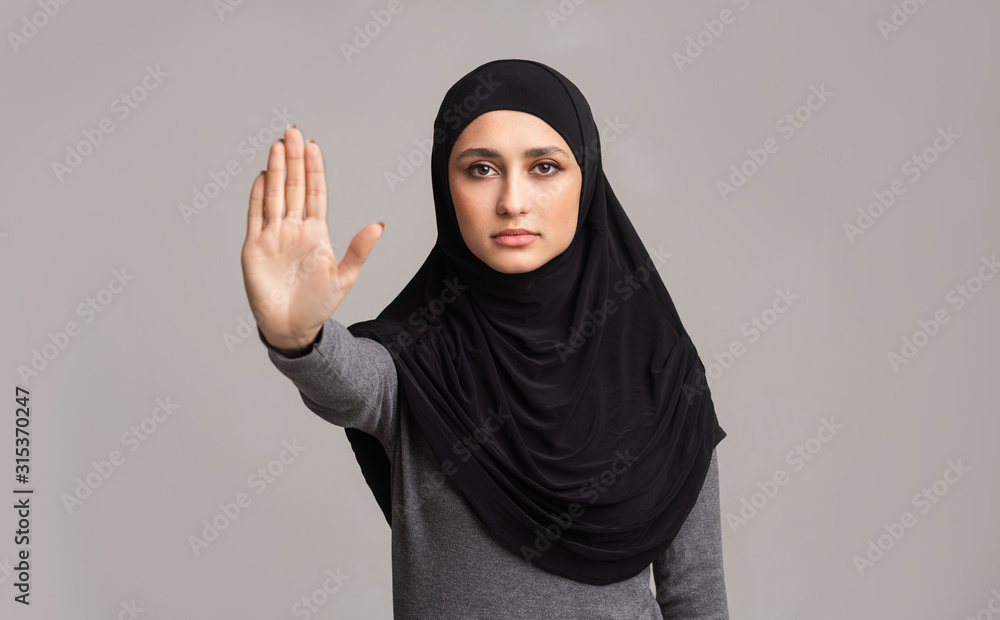 Muslim woman in hijab making stop gesture with her hand Muslim woman in hijab making stop gesture with her hand