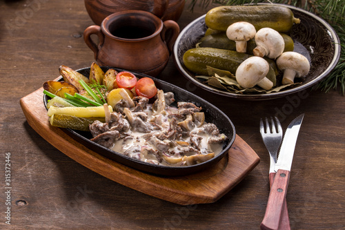 beef stroganoff with baked potatoes, mushroom and pickles on wooden table