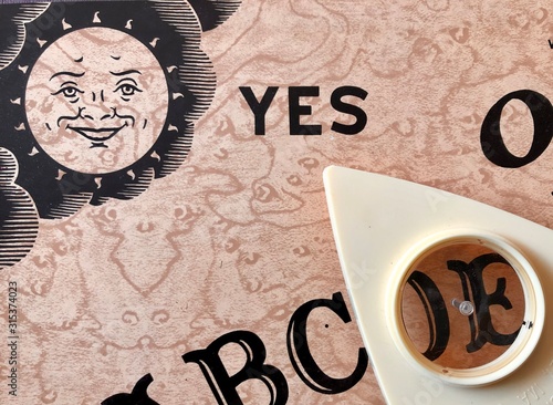 close view of ouija board with planchette pointing at the word yes