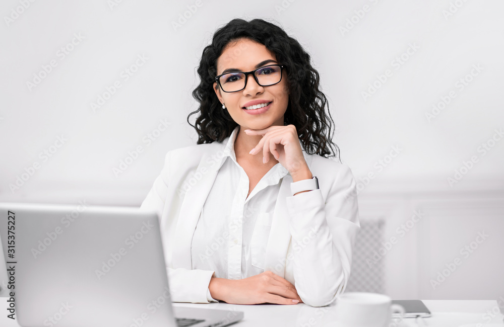 Hispanic manager smiling at camera with hand on chin Hispanic manager smiling at camera with hand on chin