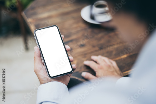 Mockup image blank white screen cell phone.man hand holding texting using mobile on desk at coffee shop.background empty space for advertise text.people contact marketing business,technology 