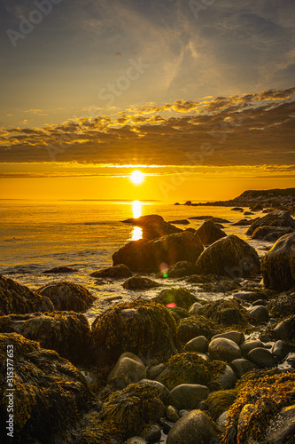 Lighthouse seascape at the beach at sunset along the rocky shoreline
