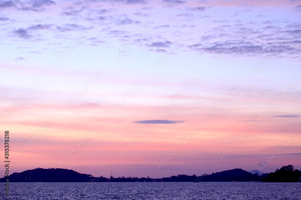 The seaside at sunset has dark shadows in the form of mountains. The seaside at sunset has dark shadows in the form of mountains.