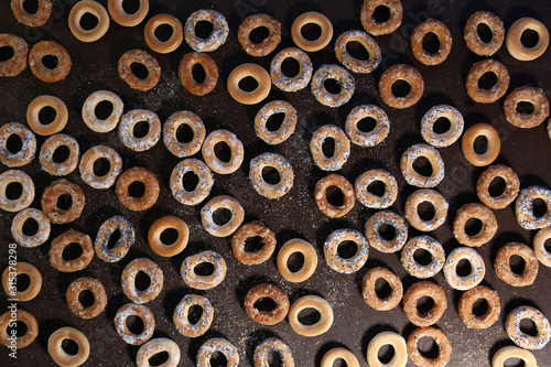Bublik cookies pattern. Ring shaped roll cookies with different glaze on dark background.. © vaitekune