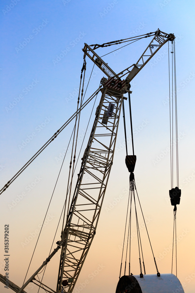 silhouette of metal crane used in construction crane close-up on blue sky
