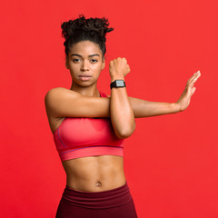 Young sporty girl doing physical exercises over red background