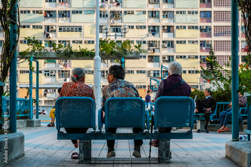 Three older women on bench from behind, old people sitting on bench -