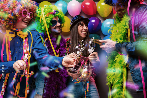 Glückliche Party Freunde feiern karneval und stoßen mit Sekt an.