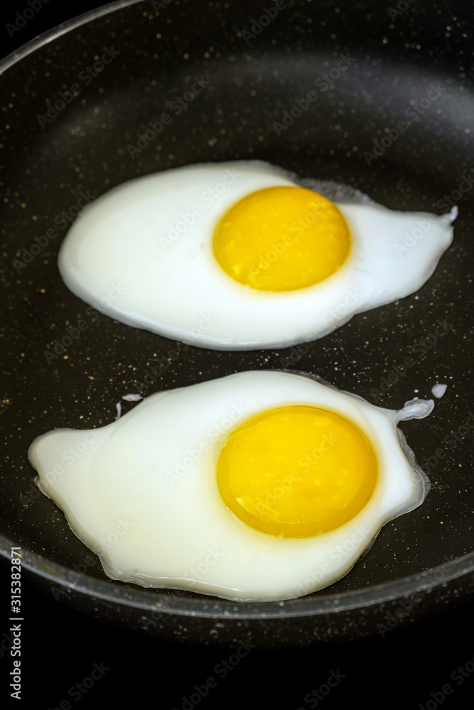 Raw fried eggs.Tasty over easy fried egg in frying pan, closeup Raw fried eggs.Tasty over easy fried egg in frying pan, closeup