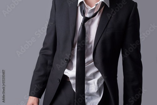 Portrait of a business man, in an untidy business suit, wrinkled clothes, sloppy look. On a gray background